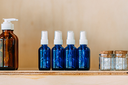 A selection of vibrant blue glass or plastic bottles on a shelf at a zero waste store. The bottles can contain shampoo, soap, and other care products and are part of a sustainable living lifestyle. The store is a small business that promotes environmental conservation and ethical consumerism. The bottles are transparent and arranged in an attractive way, and the photo is suitable for use in a variety of contexts, including retail, finance and the economy, and social issues related to environmental issues.