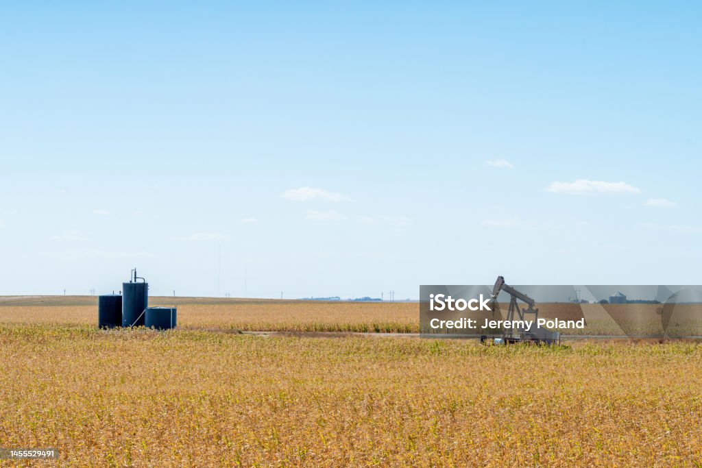 Wide Angle Shot of an Oil Pump Jack and Storage Tanks in Kansas with a Beautiful Autumn Blue Sky Background American Oil Pump Jack Producing Oil from The Ground in Kansas in the Middle of the Day on a Blue Sky in the Autumn. Image Taken Near the Town of Hays, Kansas, USA

The use of Crude Oil can be a Controversial Topic in The American Election Cycle and in Financial Discussions. Drilling Rig Stock Photo