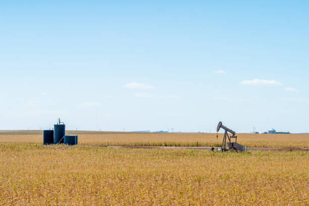 Wide Angle Shot of an Oil Pump Jack and Storage Tanks in Kansas with a Beautiful Autumn Blue Sky Background stock photo