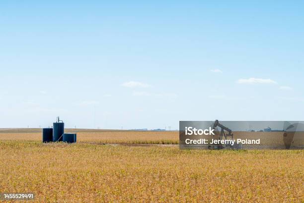Wide Angle Shot Of An Oil Pump Jack And Storage Tanks In Kansas With A Beautiful Autumn Blue Sky Background Stock Photo - Download Image Now