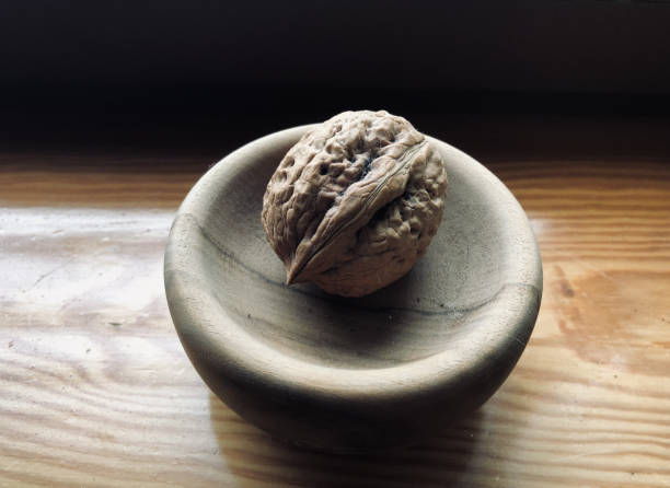 istock One big walnut in a tiny wooden bowl 1455529786