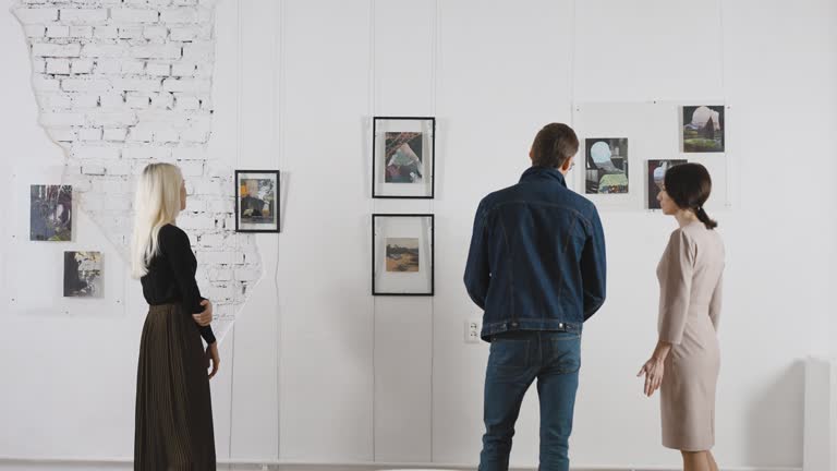 Exhibition in an art gallery. Art connoisseurs inspect the abstract works of a contemporary artist. Men and women spend time in the museum.