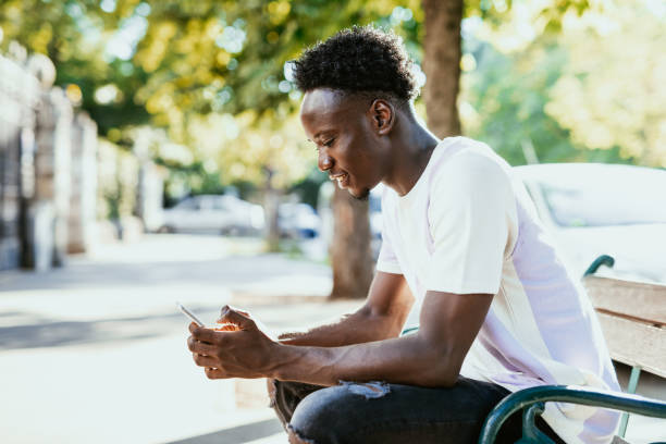 istock African man using smart phone outdoors in the city, texting and smiling 1455534465
