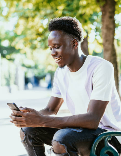istock African man using smart phone outdoors in the city, texting and smiling 1455534498