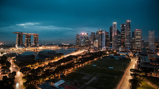 Singapore City, Singapore - 2nd December 2022: Dawn breaking over the central business district and Marina Bay in Singapore with Singapore cricket club in the foreground