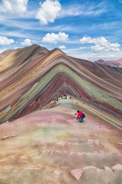Tourist climbs in the foreground of the Rainbow Mountains at an altitude of 5000 meters. stock photo