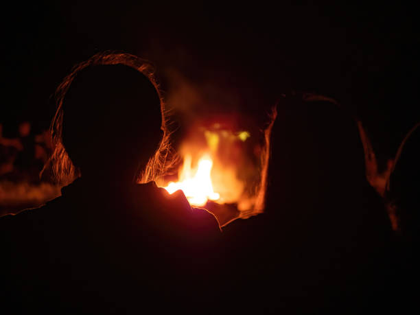 istock Two girls silhouette sitting at a campfire 1455542725
