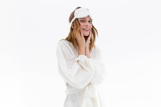 pretty young woman in silk fabric white nightgown and sleep mask looking at camera. - one woman only young women people nightie imagens e fotografias de stock