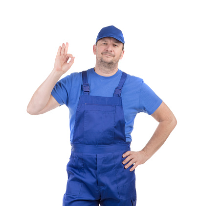 A man in a blue bib overalls shows an \