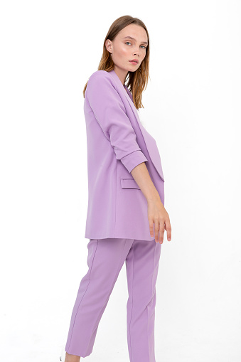 Young girl wearing purple sporty suit against white backdrop. Photomodel wearing jacket and trousers.