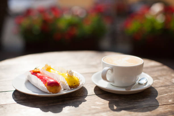 a mug of coffee on table and a delicious eclair on a plate