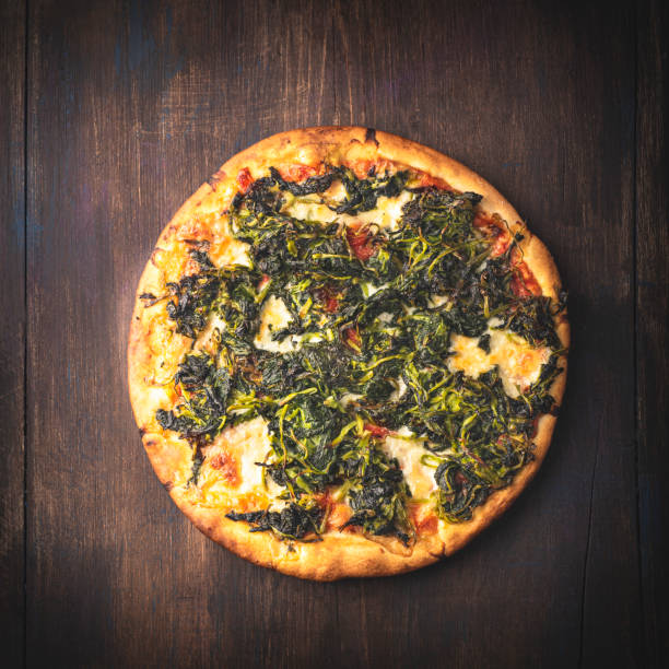 Neapolitan Italian pizza with wild broccoli or turnip greens or Friarielli ( broccoletti Romani, broccoli di rapa in Calabria, cime di rapa in Puglia ), smoked provola cheese on a wooden rustic background. Regional green pizza, square crop pizza italiana napolitana con brócoli silvestre o hojas de nabo o friarielli (broccoletti romani, brócoli di rapa en calabria, cime di rapa en puglia), queso provola ahumado sobre un fondo rústico de madera. pizza verde regional, cultivo cuadrado
