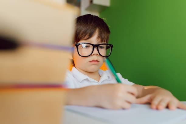 istock Child doing homework at home. Kids study and learn. Preschooler kid writing and reading. Back to school. 1455553910