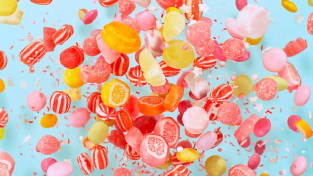 Sweet candies flying, freeze motion against pastel background stock photo