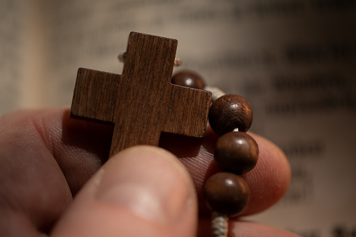 Close up of male hand holding wooden cross