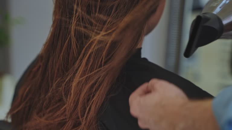 SLOW MOTION Hairstylist dries hair of female customer at beauty salon