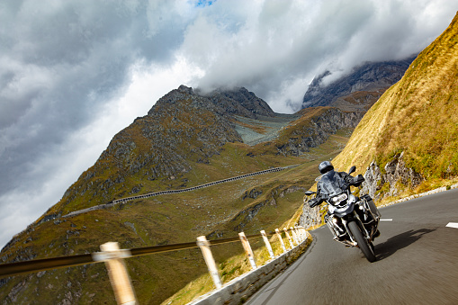 Motorbiker riding in Austrian Alps, dramatic sky. Travel and freedom, outdoor activities