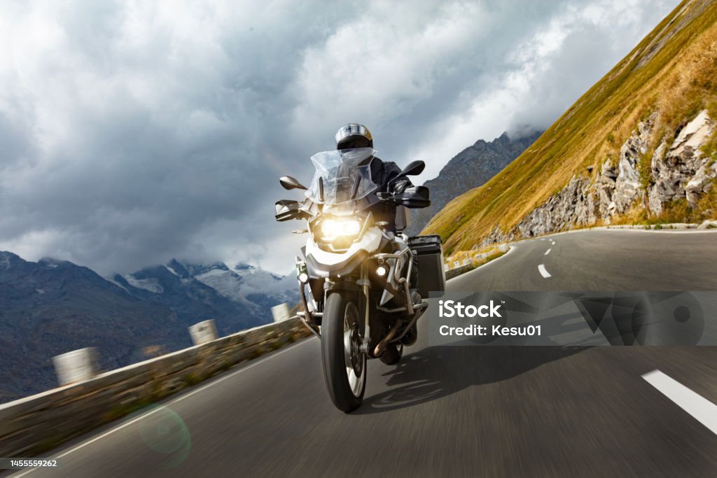 Motorbiker riding in Austrian Alps Motorbiker riding in Austrian Alps, dramatic sky. Travel and freedom, outdoor activities Motorcycle Stock Photo