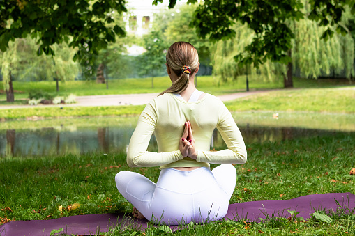young girl doing yoga in the park in nature in summer