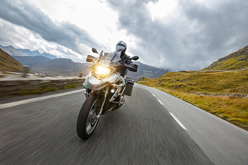 Motorbiker riding in Austrian Alps, dramatic sky. Travel and freedom, outdoor activities