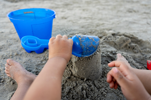 Pov of boy building a sand castle on the beach with his hands.