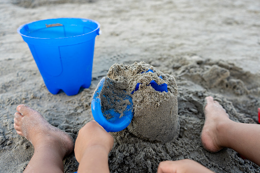 Pov of boy building a sand castle on the beach with his hands.