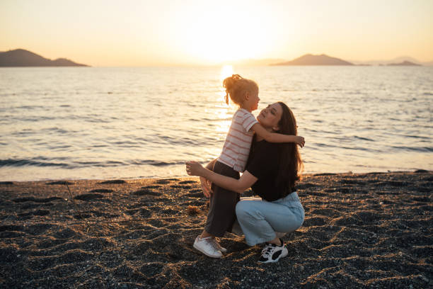 istock Mother and daughter having fun on the beach at sunset. 1455561649