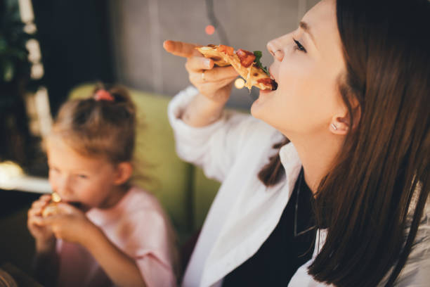 istock Mother and daughter eat pizza in a cafe. 1455561696