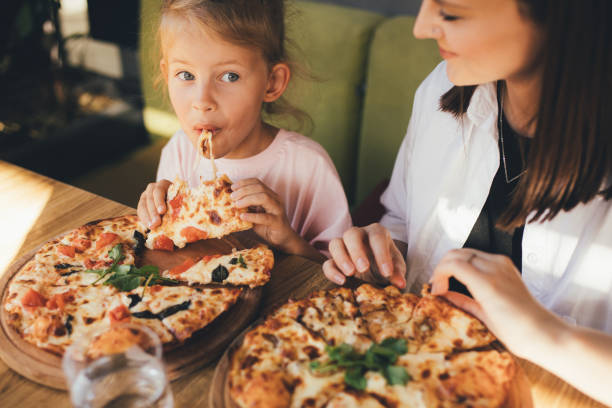 istock Mother and daughter eat pizza in a cafe. 1455561702