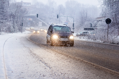 Cars on road moving slowly in winter snowfall