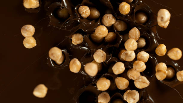 Falling Hazelnuts into Dark Hot Melted Chocolate stock photo
