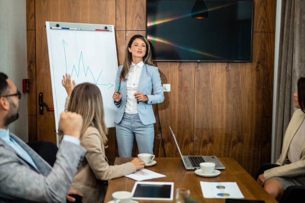 istock Young Caucasian female coach or speaker make whiteboard presentation for diverse employees in office, focused biracial woman trainer present business project on flip chart at meeting 1455565773