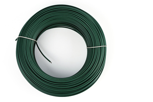 A coil of green PVC-coated wire. Isolated on a white background. Industrial texture. Selective focus.