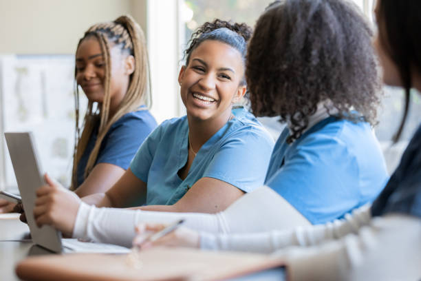 Happy young adult nursing or medical student talks with classmate in university medical training class stock photo
