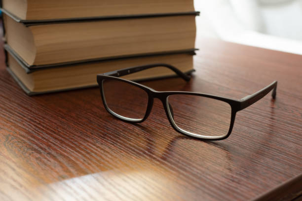 istock Stylish eyeglasses on office table on  background of stack of books 1455576974