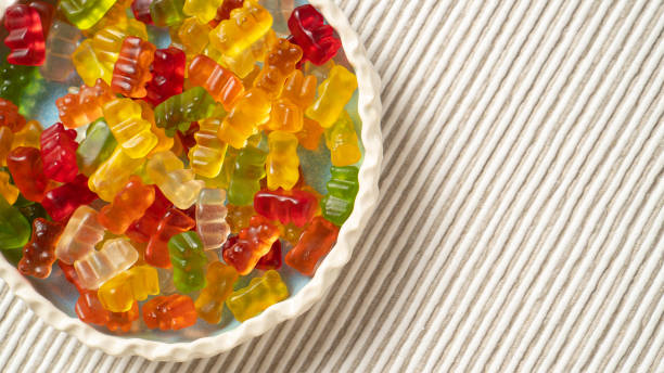 Vibrant and colorful bear-shaped jelly gummies on a white round plate on a white table, adding a delightful touch of sweetness to your design.