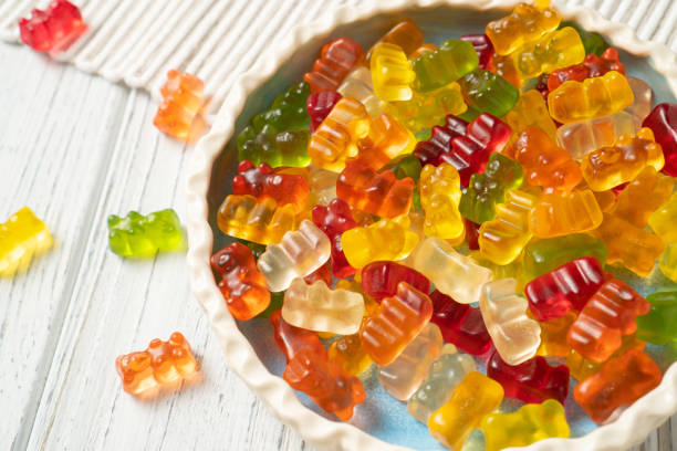 A delightful plate of sweet and colorful jelly gummies on a white table, perfect for any confectionery related project or as a treat for kids.