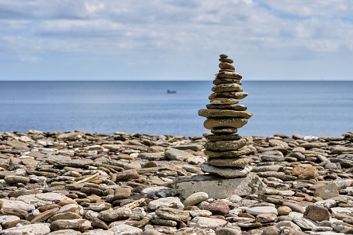 A tall cairn of granite stones overlooks the Atlantic.  Long exposure with light painting in deep twilight.