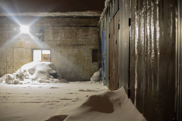istock Industrial zone in evening. Snow in garage yard. Spotlight on territory. 1455580774