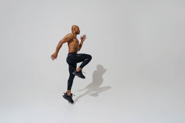 istock Professional male athlete running isolated on white studio background with shadows 1455584380