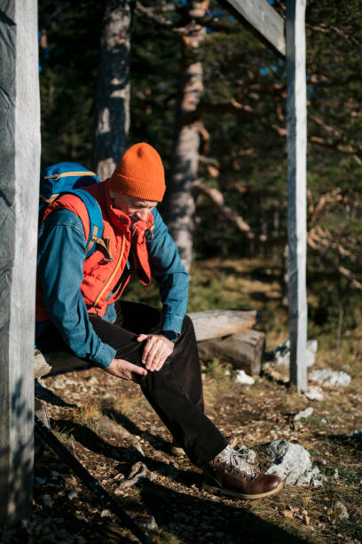 istock Senior man suffering from sore leg and knee pain during mountain hike 1455585437