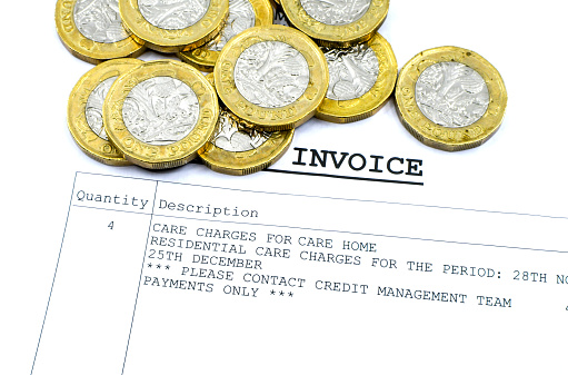 Close up view of part of an invoice for an unamed residential care home with one pound coins. Social care concept.