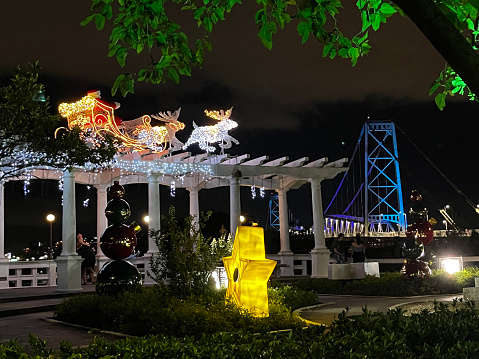 Florianópolis, Brazil - December 30, 2022: Image with the Christmas decoration at the city public park and the bridge Ponte Hercílio Luz, the longest suspension bridge in Brazil and one of the 100 largest suspension bridges in the world located in Santa Catarina state, Brazil