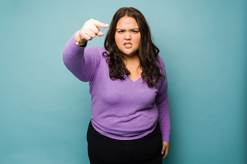 Angry mexican fat woman pointing a finger and blaming while arguing and having problems