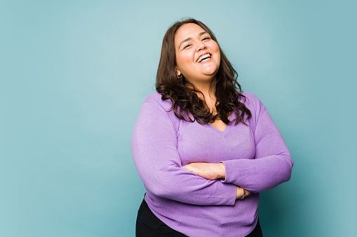Attractive obese hispanic woman looking excited while laughing and having fun