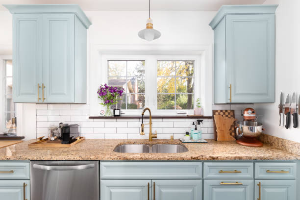 A light blue kitchen with a gold faucet and light.
