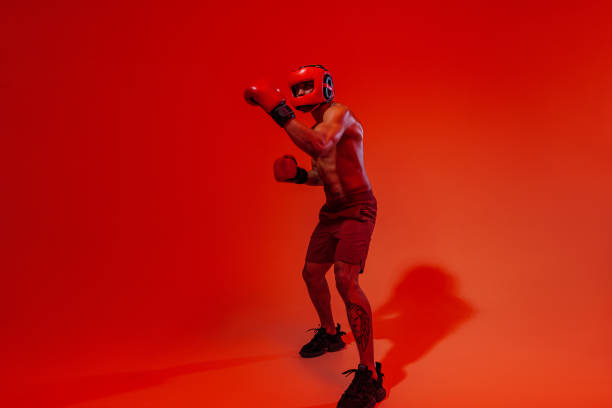 istock Sporty man wearing head guard and boxing gloves practicing for fight on studio background 1455591948