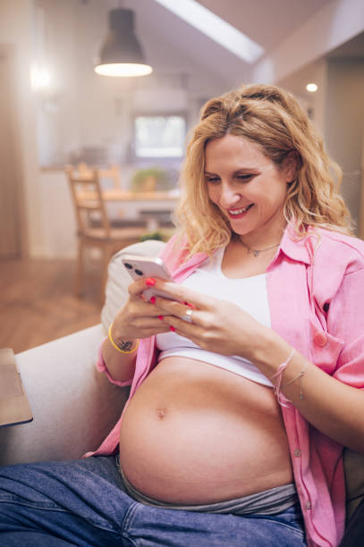 istock Beautiful pregnant woman using smartphone at home 1455593804
