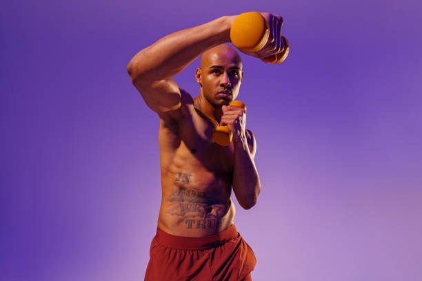 istock Muscular man doing exercise with weight dumbbells on studio background. Strength and motivation 1455595321