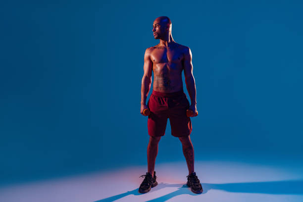 istock Muscular man doing exercise with weight dumbbells on studio background. Strength and motivation 1455595535